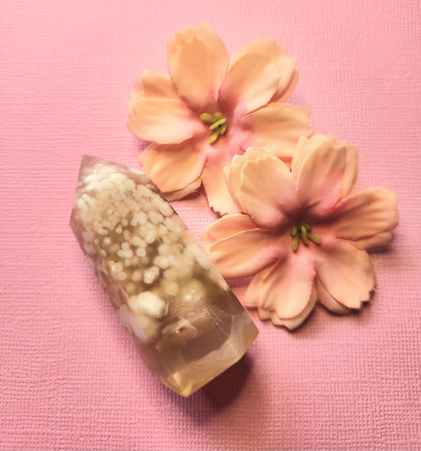 Flower Agate crystal tower showing pink, white, and green patterns, photographed on a light pink background with two flower props — polished healing crystal point for manifestation, emotional balance, and spiritual growth