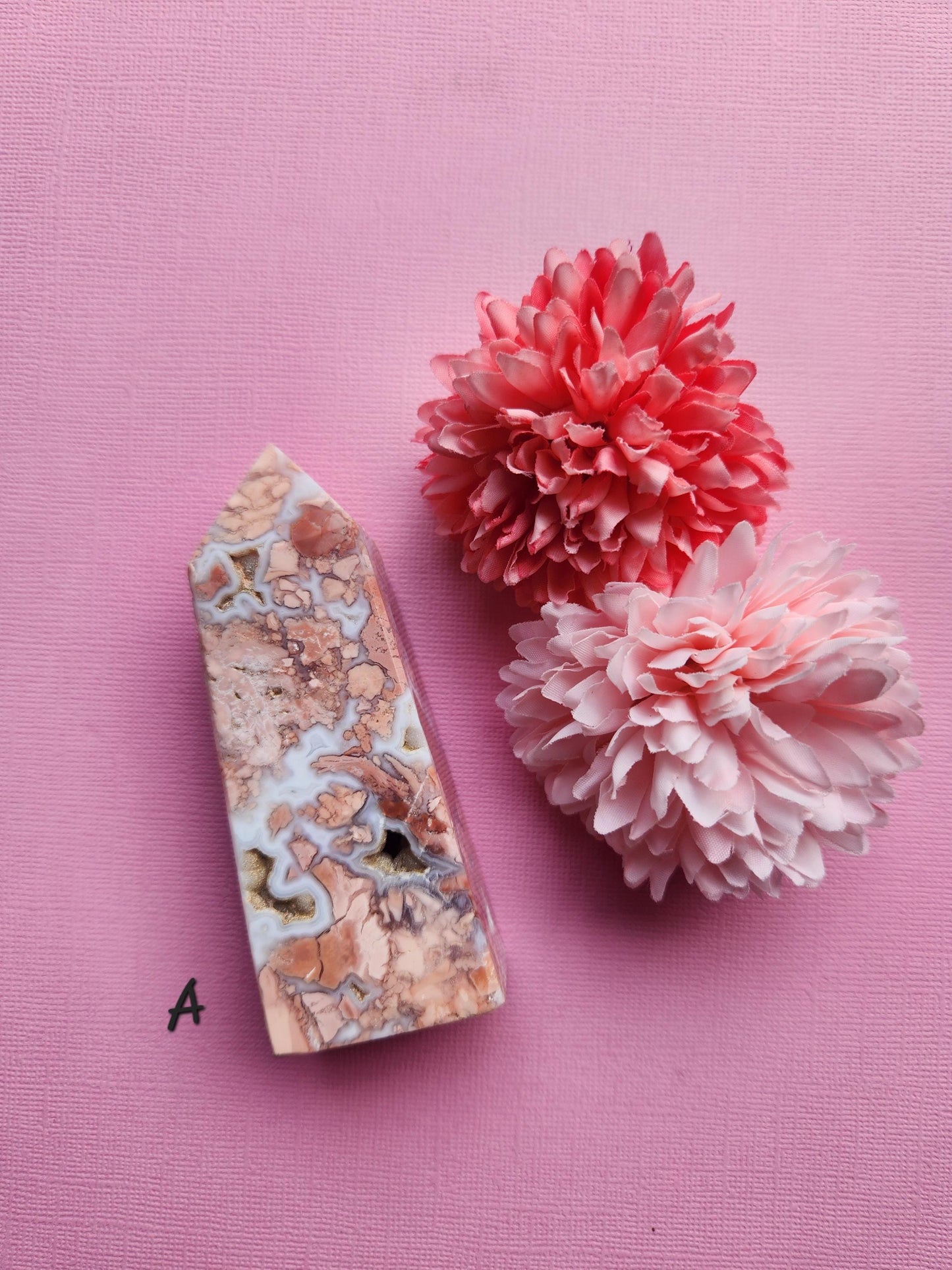 Pink Cotton Candy Agate crystal tower A standing upright on a pink background with delicate flower props featuring soft pastel banding polished agate point for crystal healing decor and gift