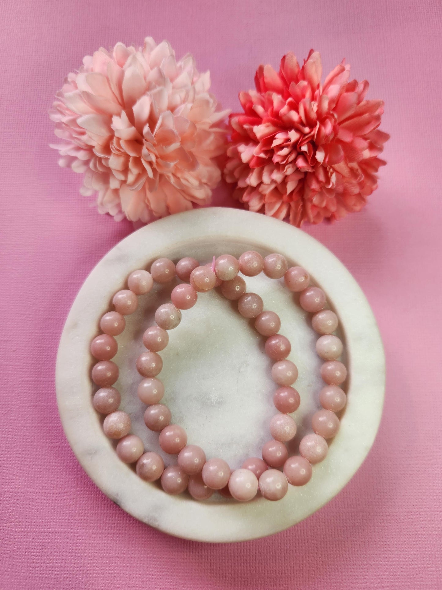 Natural Pink Opal 8mm crystal bracelets shown in a white dish with decorative flower props on a pink backdrop, smooth round pink opal beads bracelet for self love heart healing soothing energy and mindful gifting