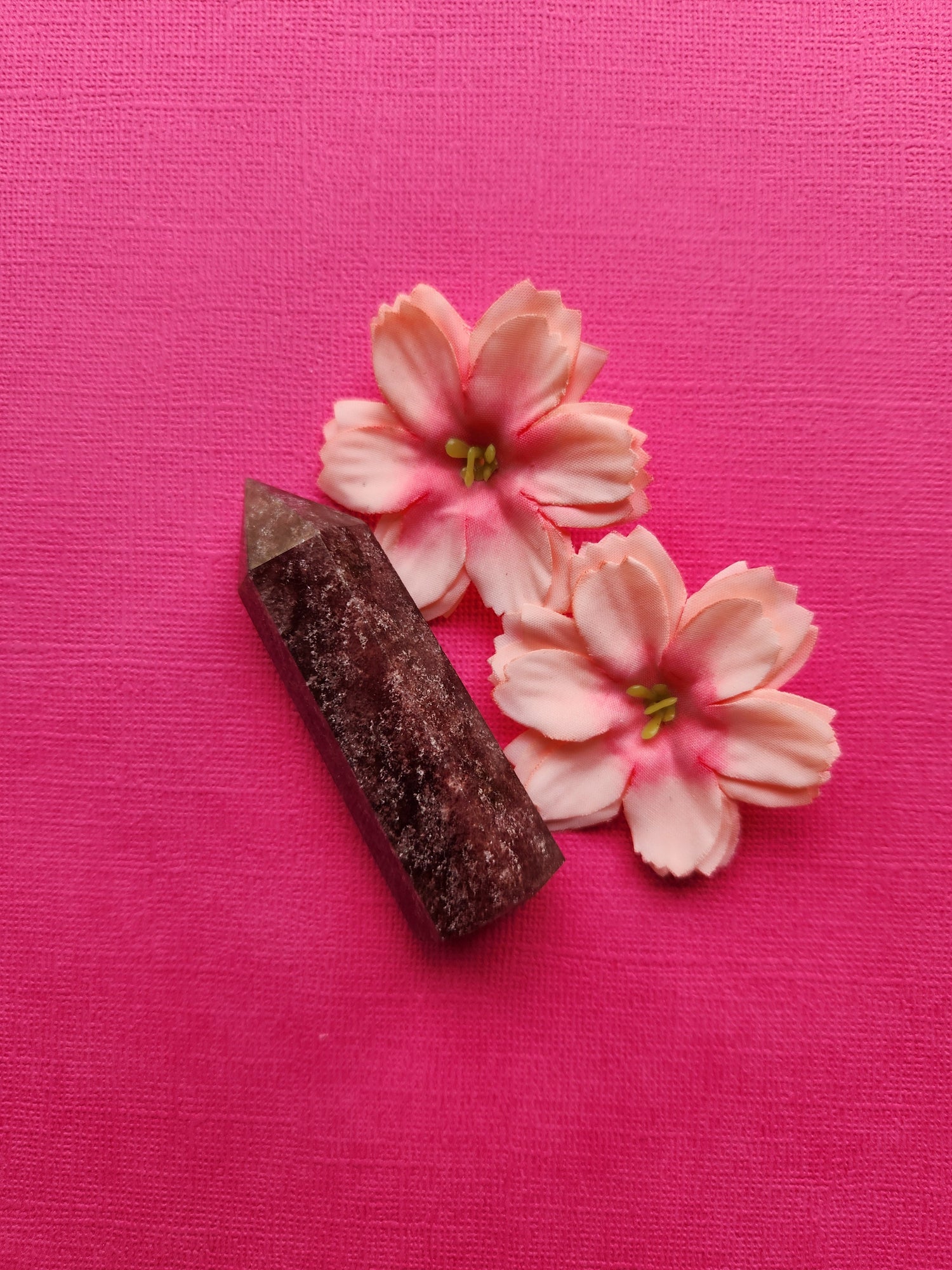 Strawberry quartz tower with two pink flowers on bright pink background – polished healing crystal tower for energy and meditation