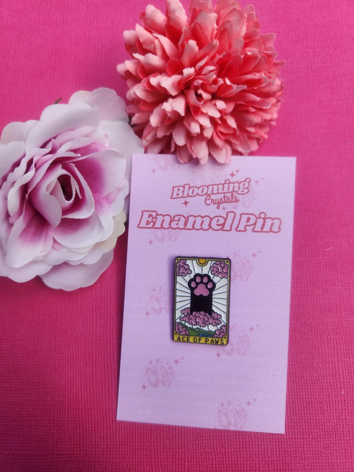Ace of Paws cat tarot enamel pin featuring a single cute cat paw in the centre, pastel pink white and yellow design, mystical tarot card inspired feline paw badge, kawaii witchy enamel pin for cat lovers, spiritual aesthetic lapel pin, cute collectible pin for bags jackets and pin boards