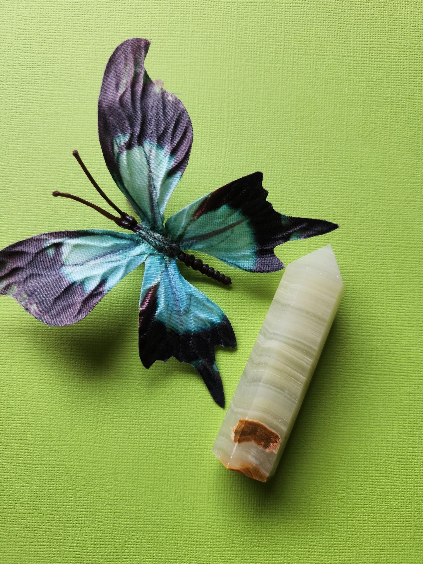 Afghan Jade Tower photographed from a side angle against a bright green background, revealing the crystal’s polished facets and rich green color variations. This natural jade tower is a powerful healing stone used for grounding, spiritual healing, and chakra alignment. Its elegant shape makes it a beautiful addition to any crystal collection or altar setup.