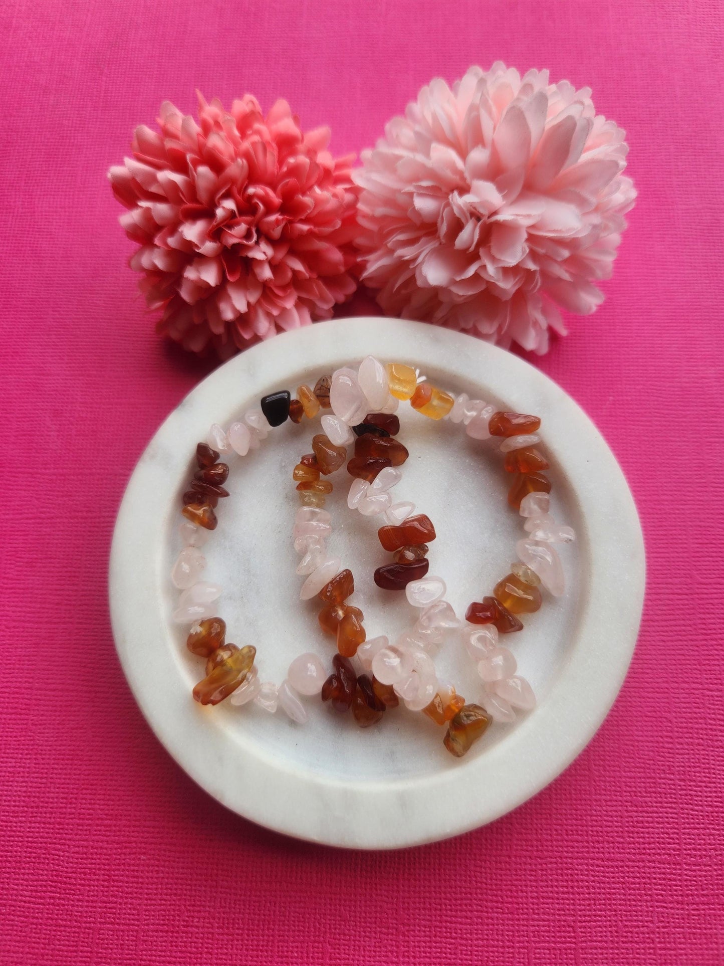 Rose Quartz and Carnelian chip bracelet featuring natural pink rose quartz and vibrant orange carnelian crystal chips on one stretchy bracelet, handmade mixed crystal chip bracelet, love and confidence crystal jewelry, heart chakra and sacral chakra bracelet, emotional healing gemstone bracelet, feminine boho crystal bracelet, rose quartz carnelian bracelet for gifting photographed close up