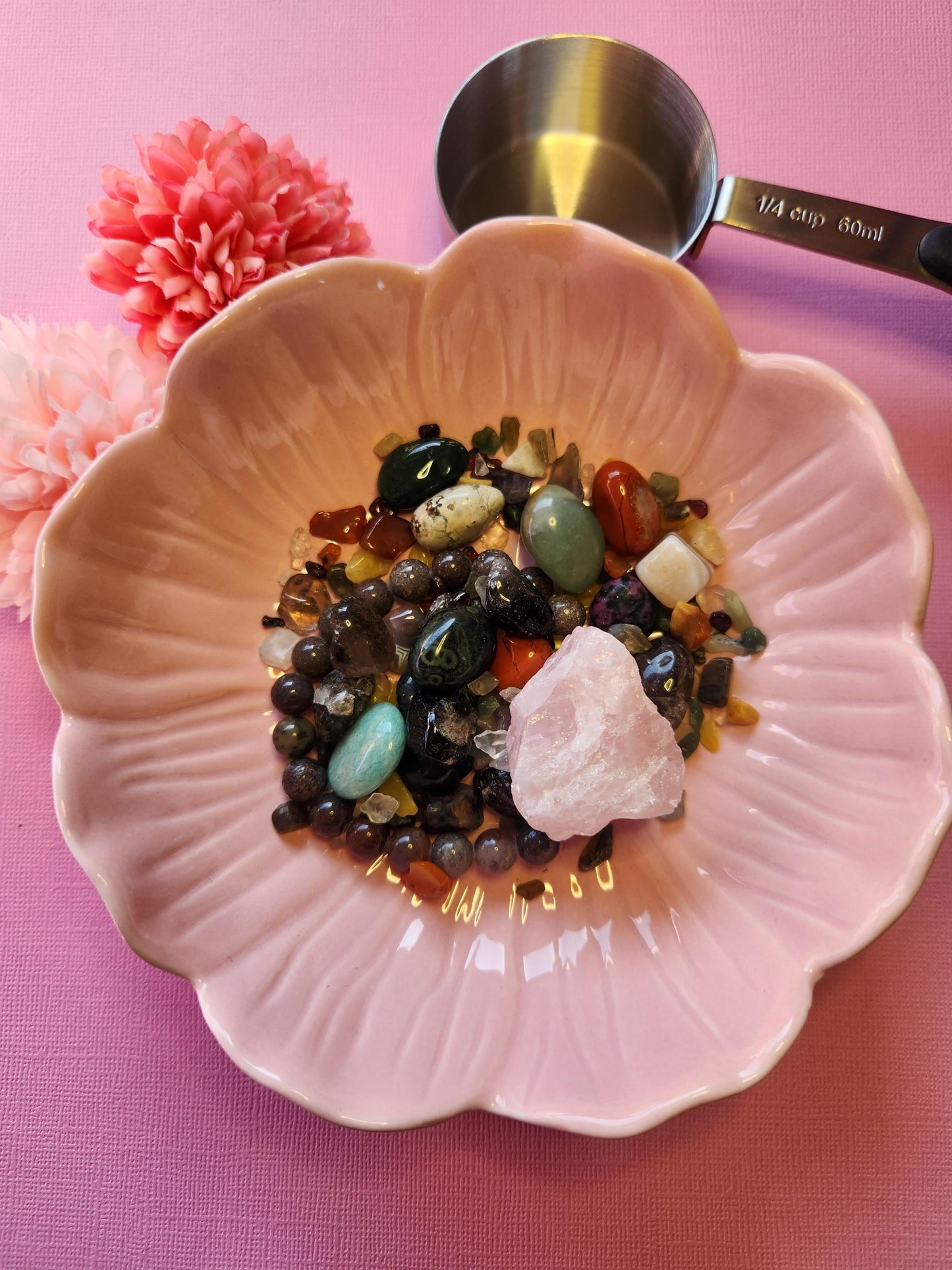 Example scoop of Crystal Confetti on a pink background, featuring a variety of tumbled stones and raw chips in assorted colors and sizes. This sample shows what may be included in a 1/4 cup mystery scoop—great for beginners, spiritual practices, or DIY crystal projects. The pink backdrop enhances the vibrant tones of the crystals, making them pop with energy and charm.