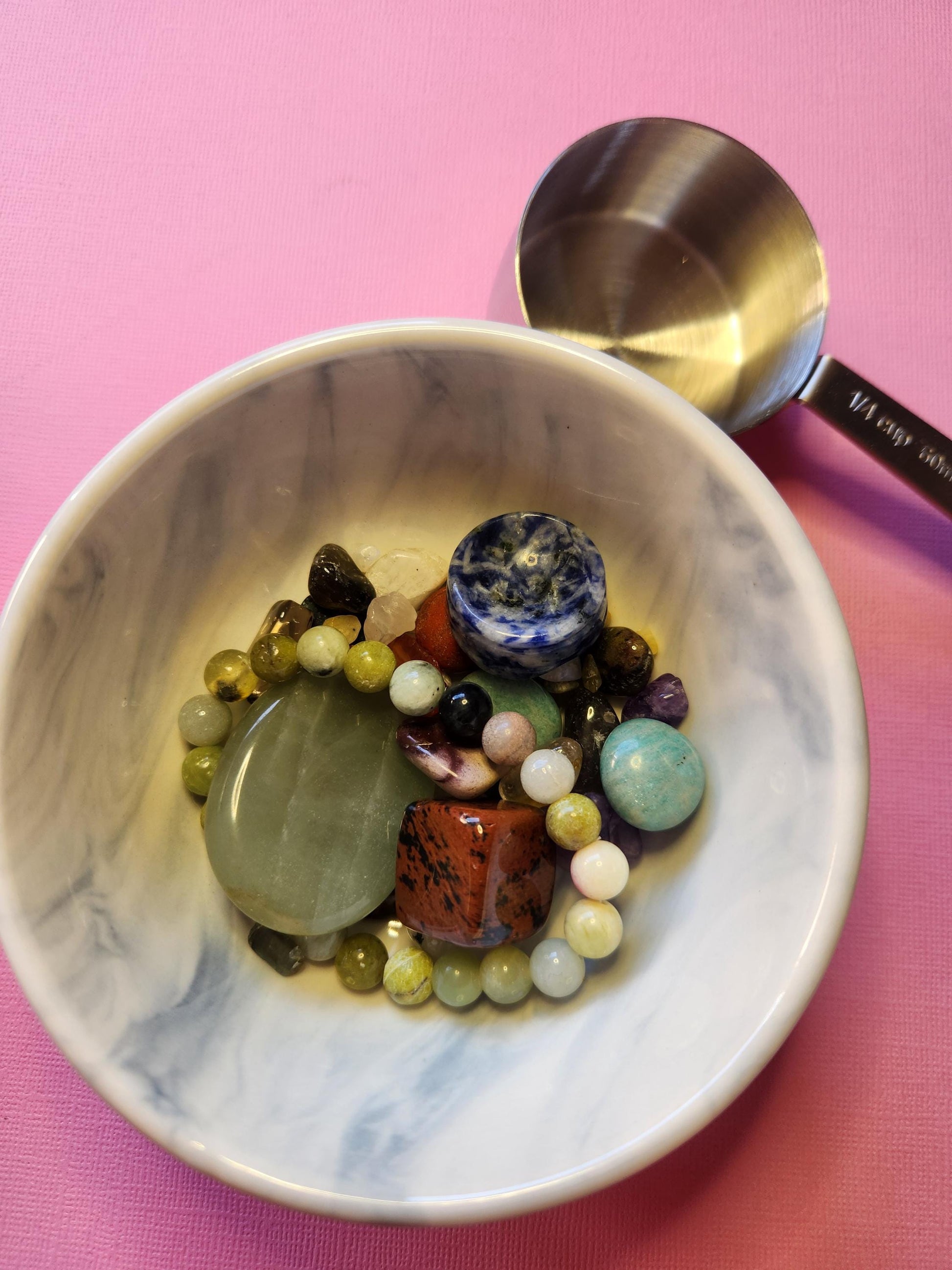 Random selection of crystals from a confetti scoop shown on a pink background, with polished and natural textures. The crystals vary in shape, color, and energetic properties, making this ideal for spiritual kits, altar decor, or crystal grid supplies. This image shows what you might receive in a 1/4 cup scoop of mixed crystals—perfect for anyone who loves surprise metaphysical treasures.