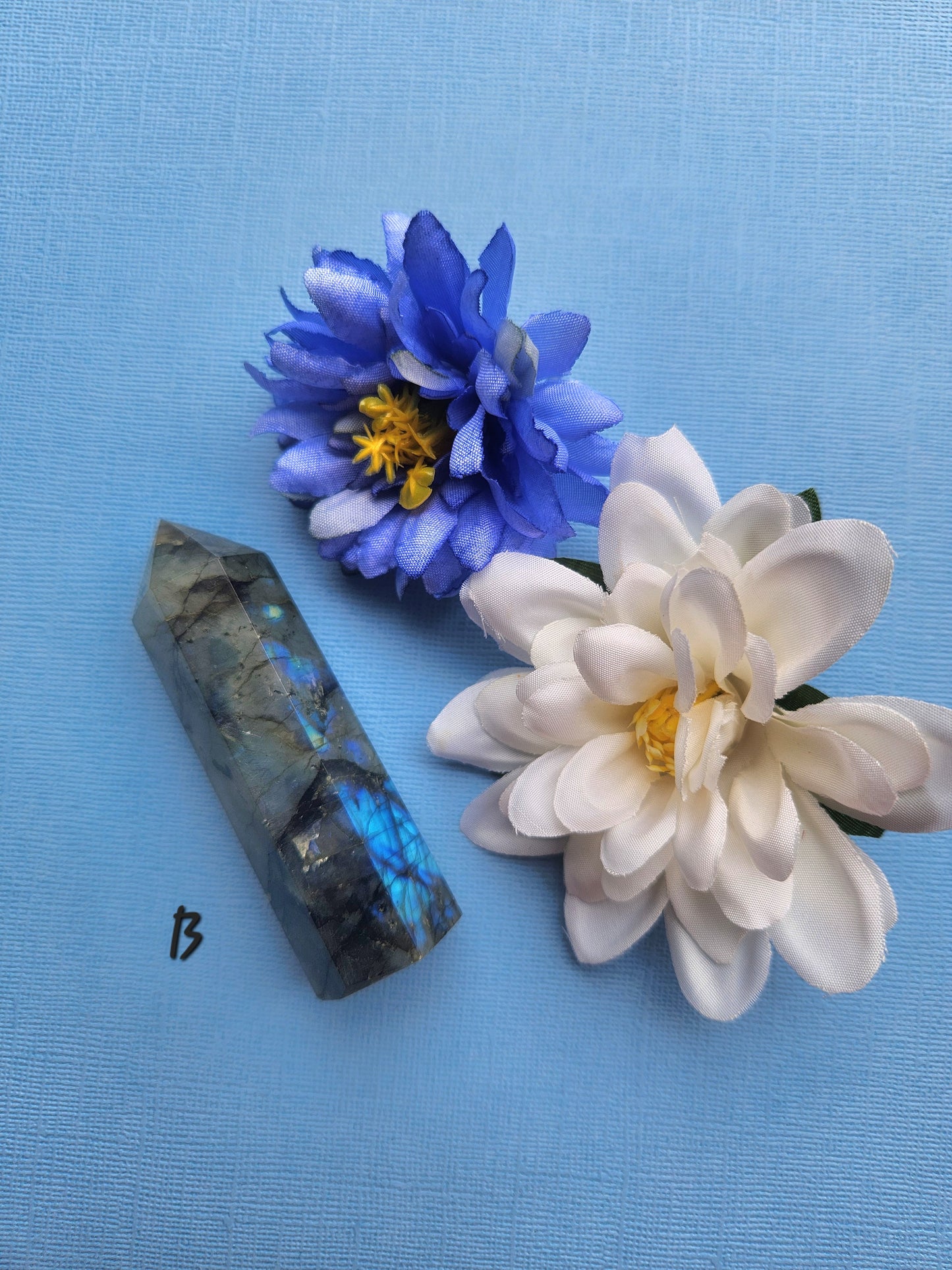 Labradorite Tower B featuring strong blue labradorescence and a blue butterfly prop on a blue background, polished labradorite gemstone tower for protection, third eye chakra work, transformation energy, and metaphysical crystal displays