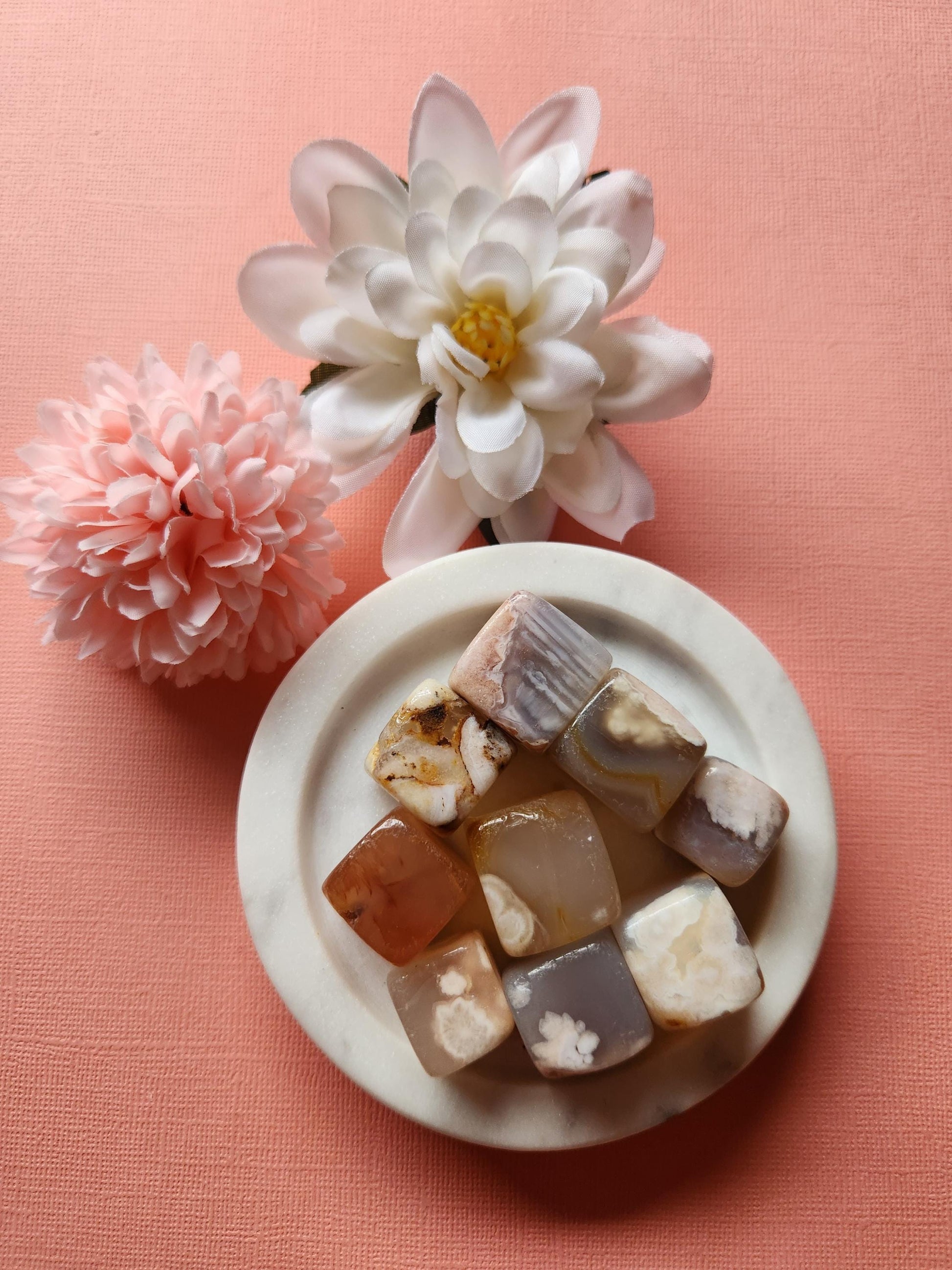 Beautiful natural Flower Agate cubes displayed on a soft pink background, featuring polished healing crystals with unique floral and dendritic patterns. These Flower Agate gemstones are perfect for crystal collectors, meditation, chakra balancing, stress relief, spiritual healing, and metaphysical uses. Ideal for gifting, home decor, energy work, grounding, and enhancing mindfulness practices.