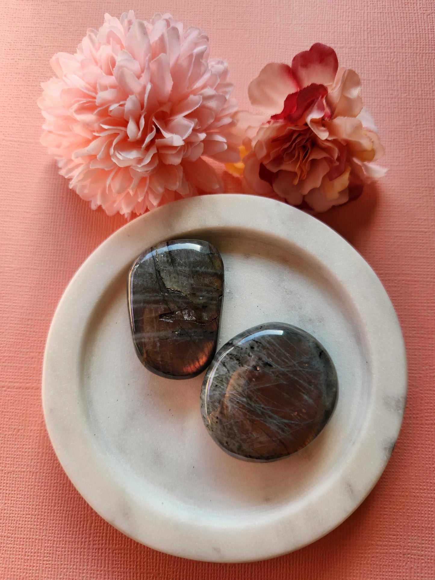 Two polished Labradorite palm stones with stunning pink and yellow flash displayed on a soft pink background. These flashy healing crystals are perfect for protection, spiritual energy work, meditation, and chakra balancing. Labradorite is known for enhancing intuition and shielding against negativity. Ideal for reiki sessions, crystal collectors, or as thoughtful metaphysical gifts.
