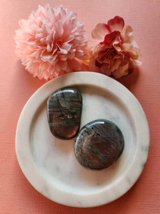 Two polished Labradorite palm stones with stunning pink and yellow flash displayed on a soft pink background. These flashy healing crystals are perfect for protection, spiritual energy work, meditation, and chakra balancing. Labradorite is known for enhancing intuition and shielding against negativity. Ideal for reiki sessions, crystal collectors, or as thoughtful metaphysical gifts.