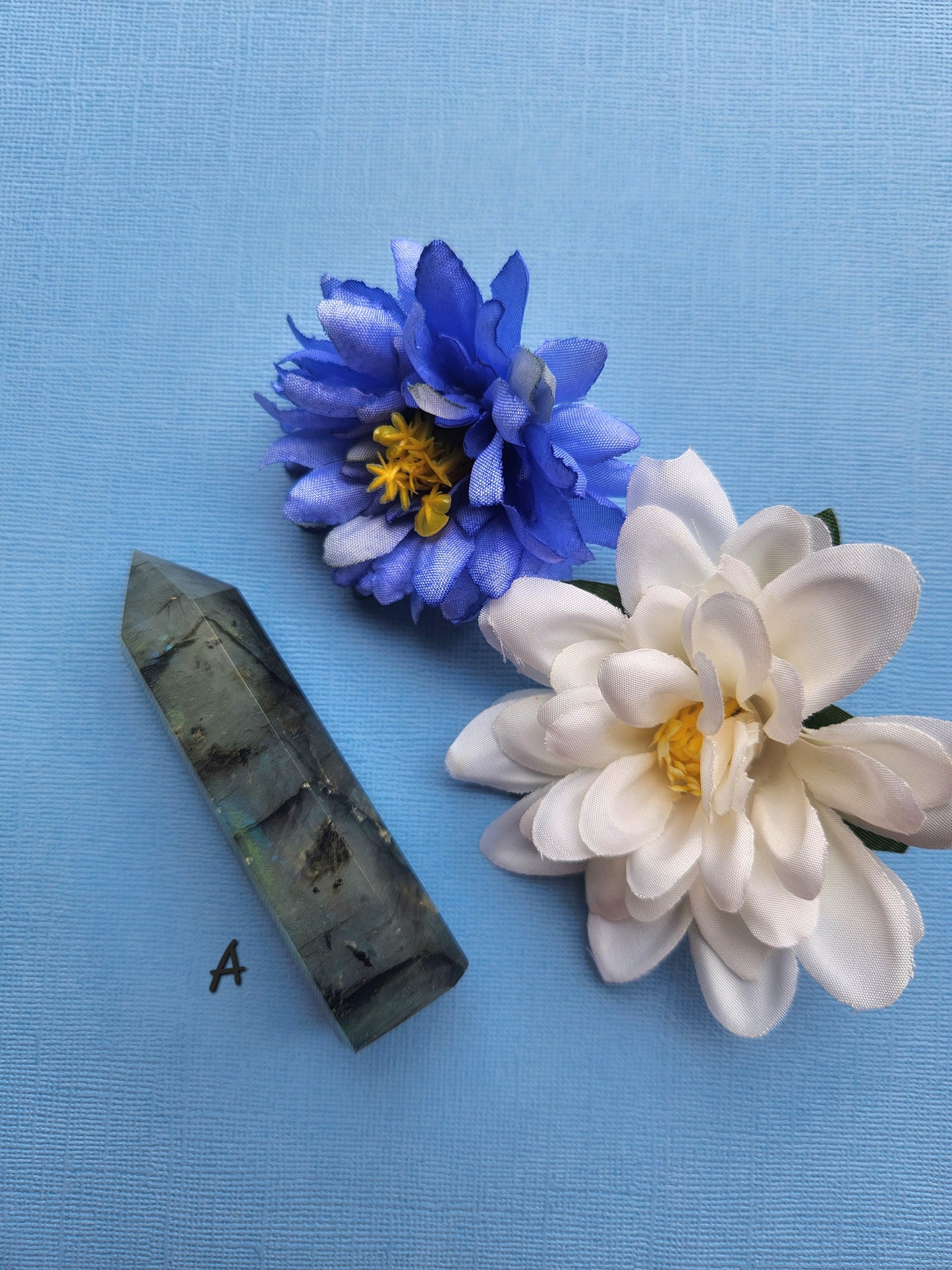 Labradorite Tower A shown up close with vivid blue flash beside a blue butterfly prop on a blue backdrop, premium labradorite crystal point for intuition, psychic development, energy shielding, and spiritual healing décor