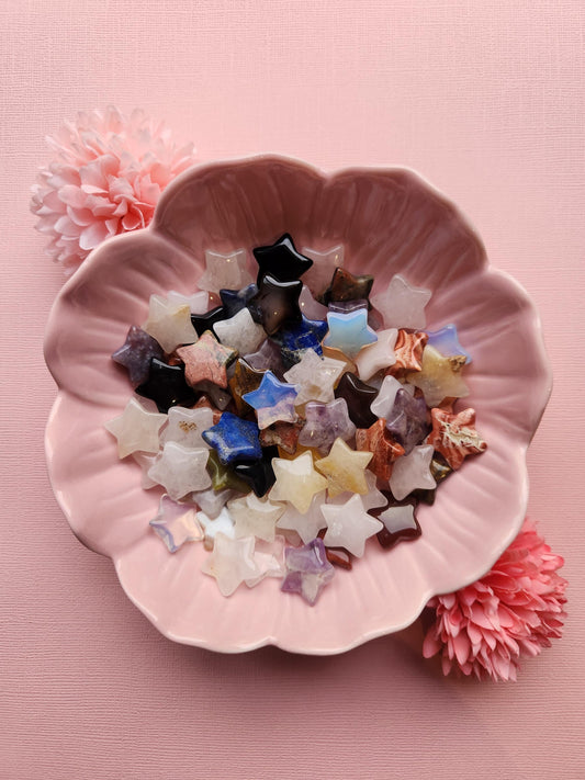 Mystery mini crystal stars intuitively chosen from natural gemstones, displayed on a soft pink background. Each tiny star is a surprise, perfect as a unique crystal gift, pocket totem, or witchy decor accent. These small carved stars bring positive energy, healing vibes, and magical charm to any crystal collection or spiritual practice. Ideal for meditation, energy work, and enchanting home decorations.