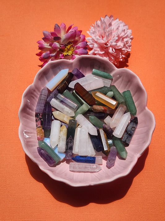 Random selection of mystery mini crystal towers arranged in a pink flower bowl with decorative flower props on an orange background, polished gemstone crystal points for intention setting meditation and mindful gifting