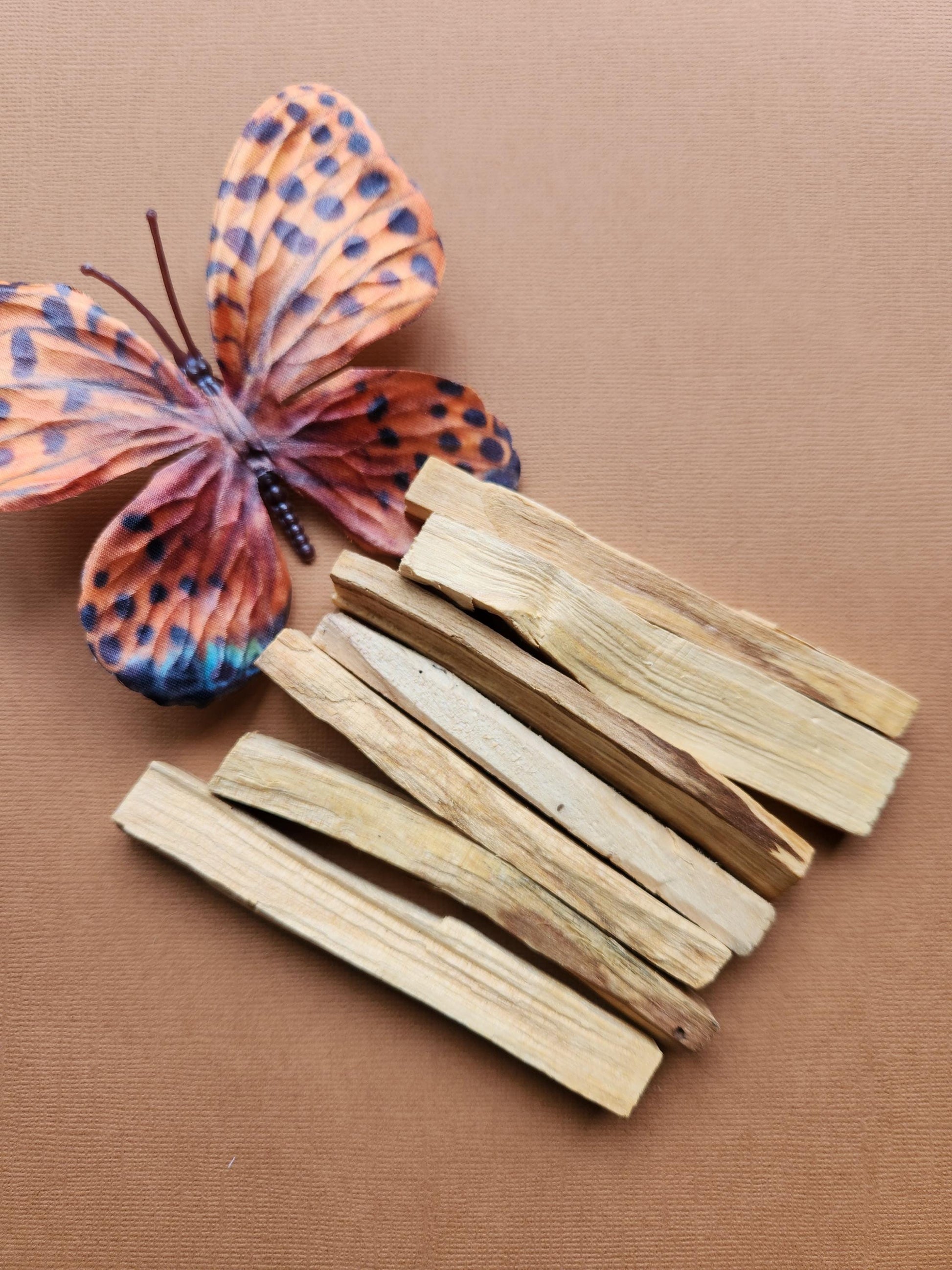 Palo Santo sticks displayed on a warm brown background, showcasing their natural wood texture and earthy tones. These sacred wood sticks are traditionally used for smudging, energy clearing, meditation, and spiritual rituals. The rich brown backdrop complements the organic, rustic appearance of the Palo Santo, emphasizing its grounding and cleansing properties. Perfect for holistic wellness, spiritual practices, and natural incense lovers.