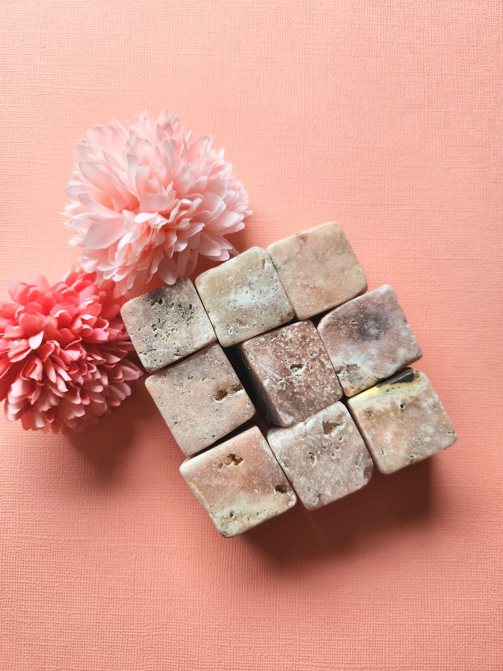 Nine pink amethyst cubes arranged in a 3x3 square formation, showcasing their soft pink hues and polished surfaces. These healing crystals are perfect for meditation, calm energy, and spiritual decor. The organized layout highlights the smooth, glossy finish and uniform shape, ideal for crystal collectors and chakra healing.