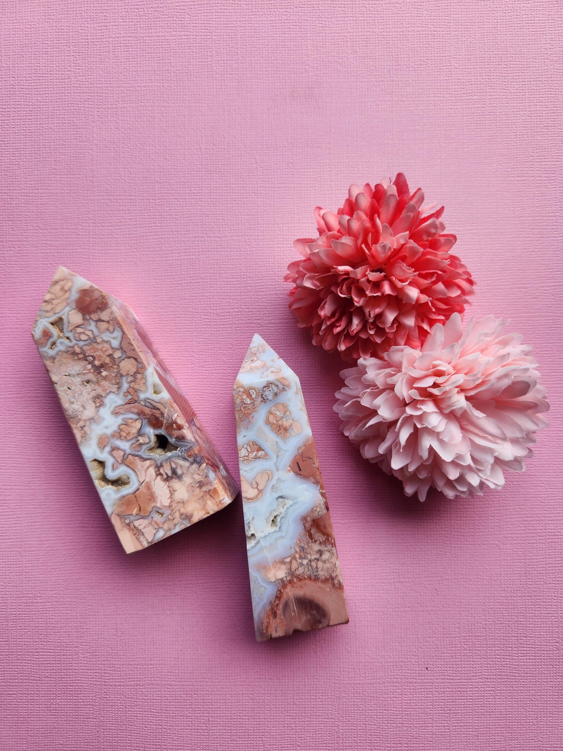 Pink Cotton Candy Agate crystal towers pair displayed upright on a pink background with soft flower props showcasing polished pastel agate points for crystal decor healing crystals and collector display