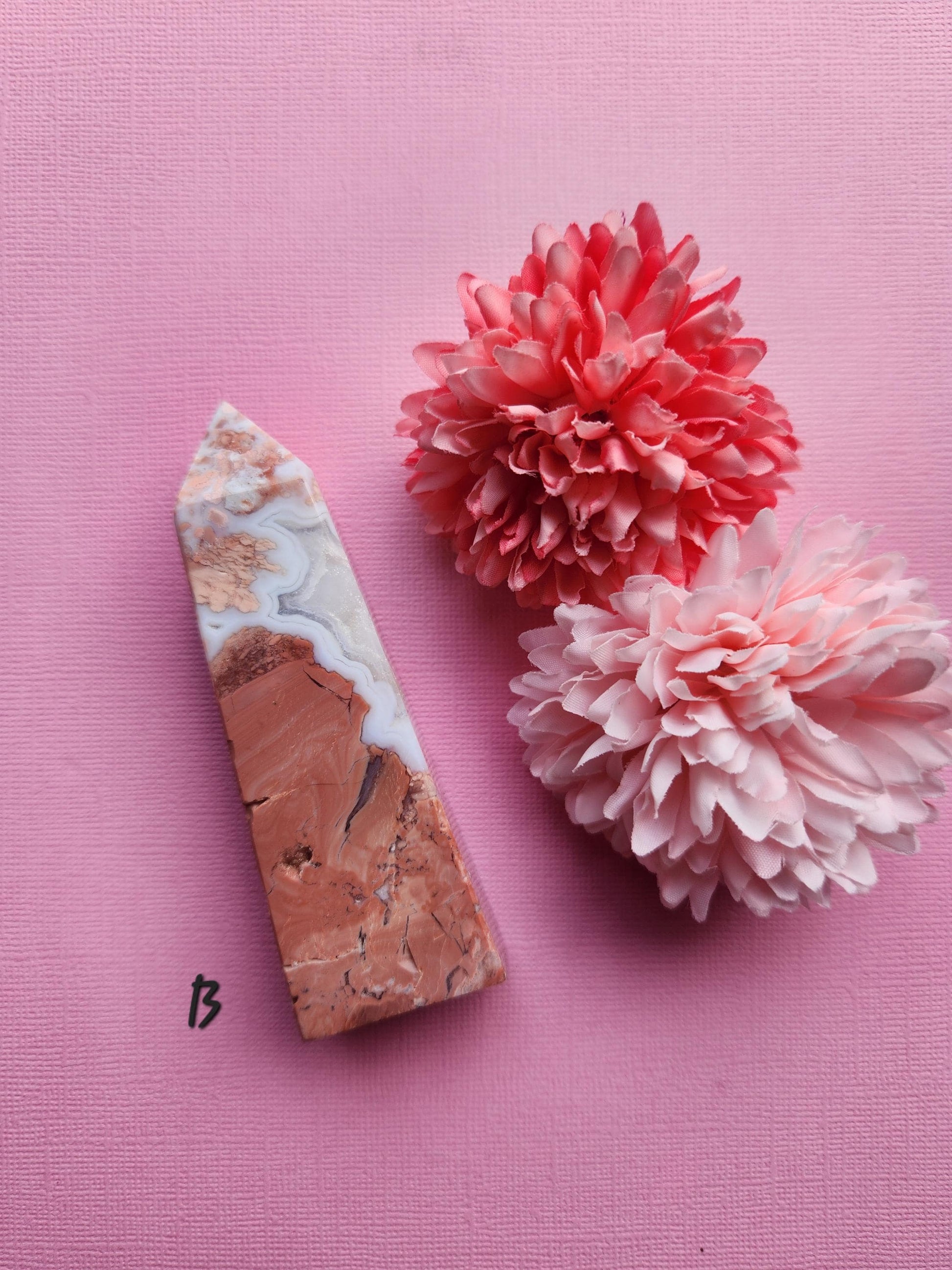 Pink Cotton Candy Agate crystal tower B photographed upright on a pink background with floral props highlighting smooth pastel agate patterns polished crystal point for home decor and metaphysical use
