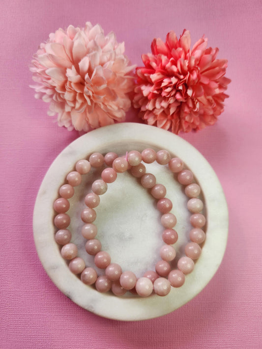 Natural Pink Opal 8mm crystal bracelets shown in a white dish with decorative flower props on a pink backdrop, smooth round pink opal beads bracelet for self love heart healing soothing energy and mindful gifting