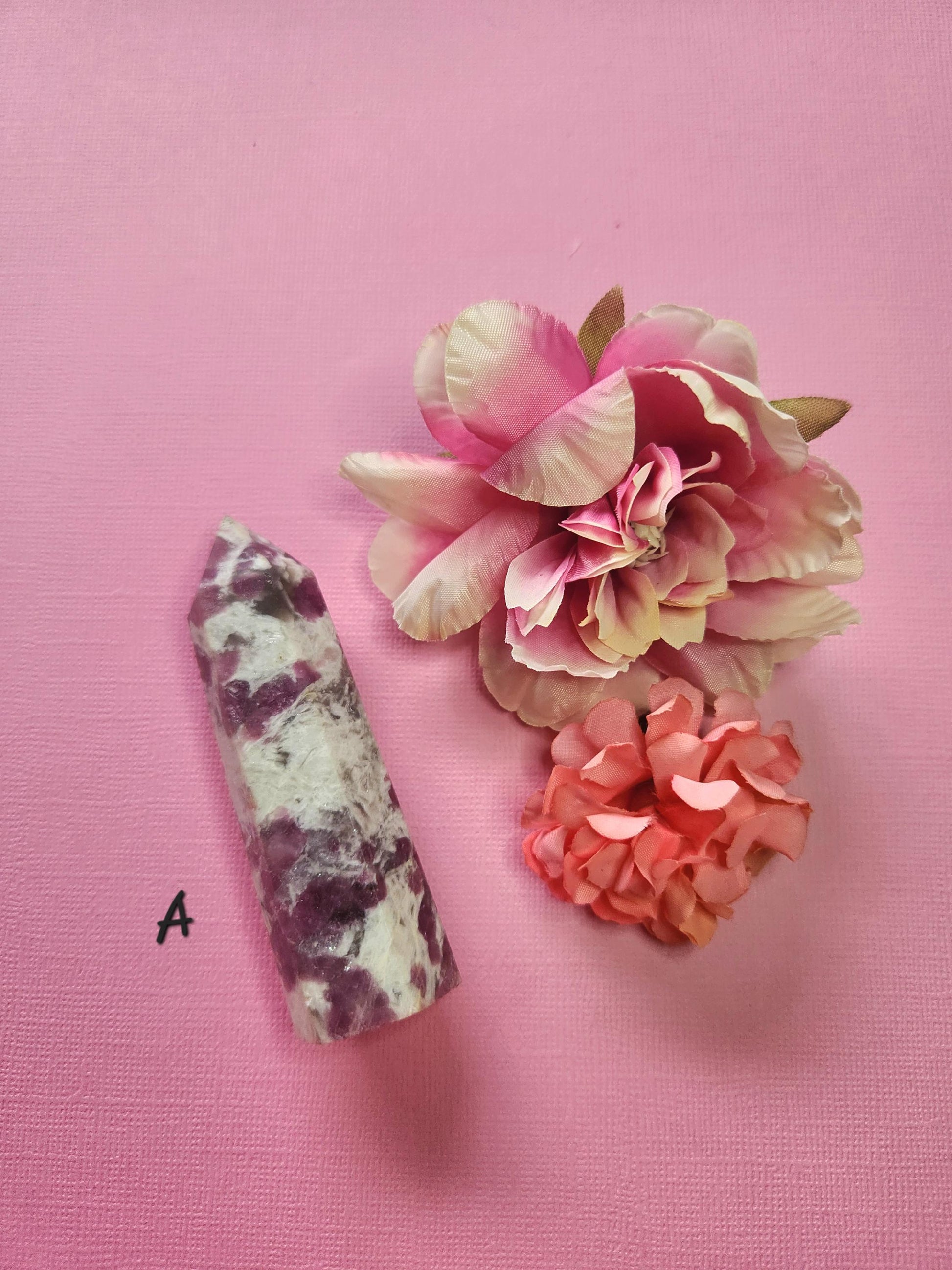Pink tourmaline tower A showcasing vibrant pink crystal striations, polished gemstone point with two flower props on a pink background, natural healing crystal for heart chakra, emotional support, energy cleansing and spiritual décor