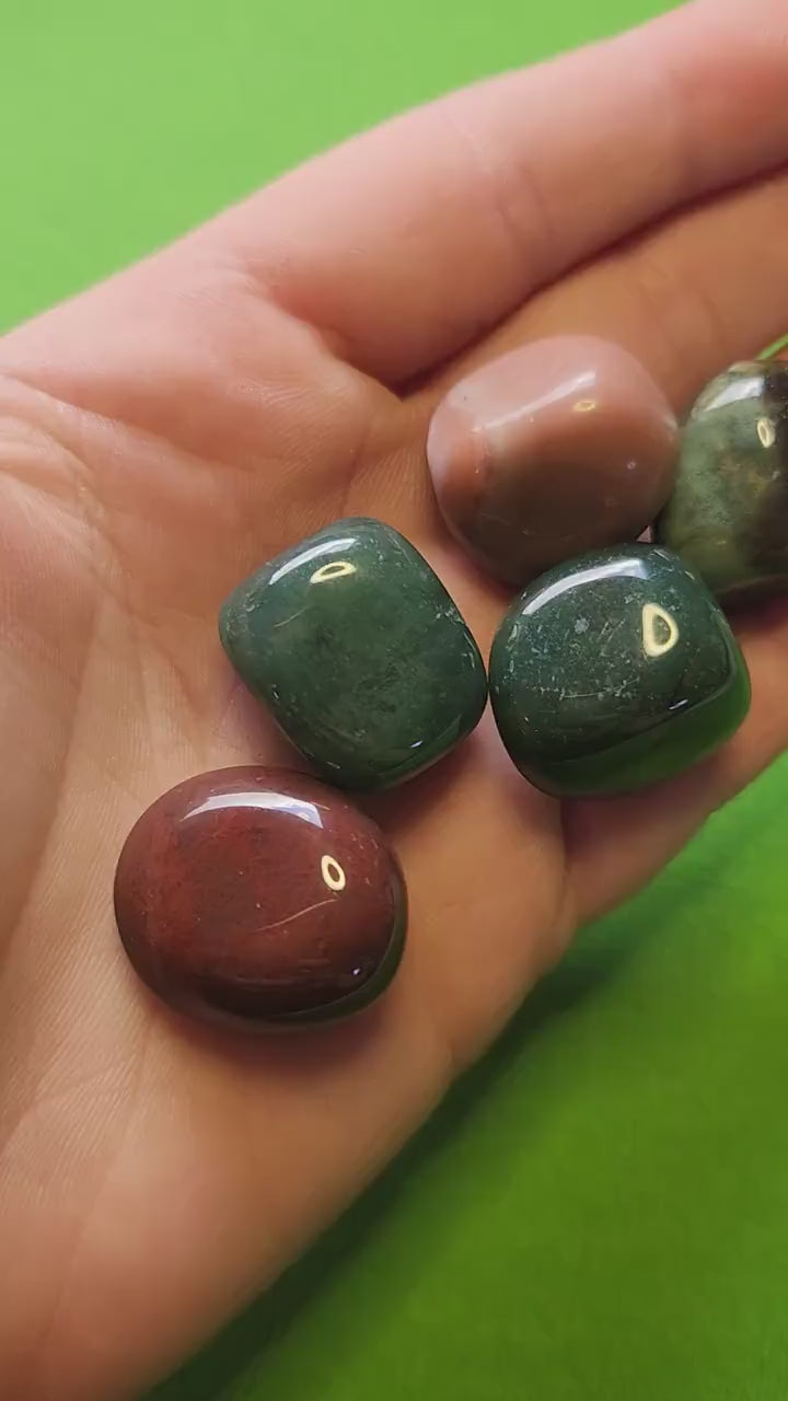 Video showcasing polished Ocean Jasper tumbles up close on a bright green background. Features natural multicolored patterns, including green, pink, and cream swirls. Perfect for crystal collectors, crystal healing, and gemstone enthusiasts