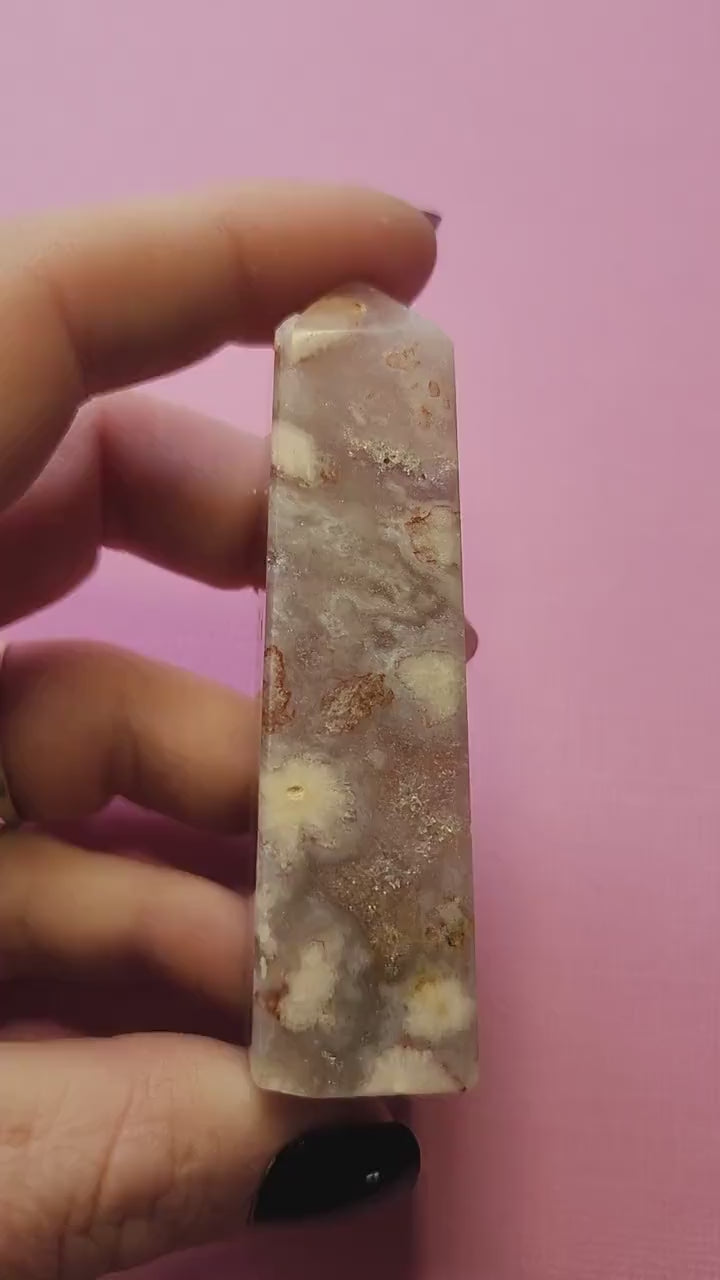 Video of a person showcasing a Pink Amethyst tower on a light pink background. Features a polished, pointed crystal tower in soft pink hues, perfect for crystal collectors, healing, meditation, and spiritual décor.