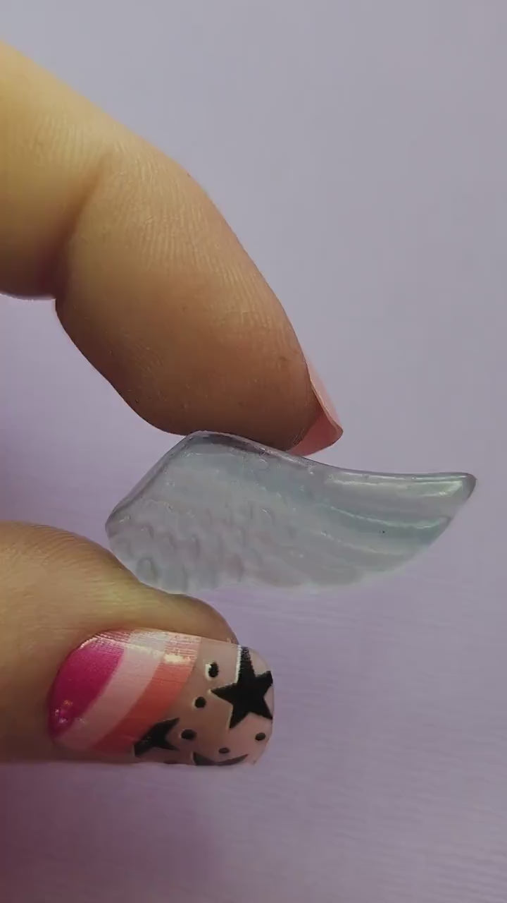 Close-up video of a single fluorite mini wing carving held in hand, highlighting the polished details and natural purple, green and blue fluorite banding as it catches the light against a lavender backdrop. Ideal for fluorite carvings, angel wing crystals and collectible gemstone accents