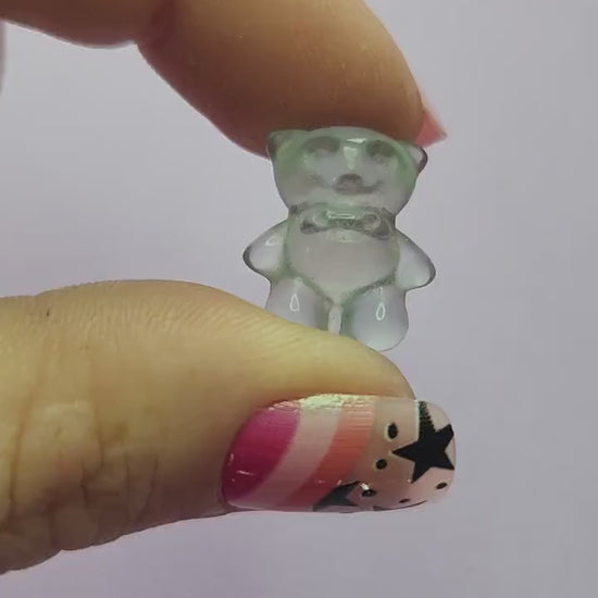 Smooth close-up video of a single fluorite mini bear carving held in hand, showing polished details and natural bands of purple, green and blue fluorite against a lavender backdrop. Ideal for fluorite carvings, mini crystal animals and collectible gemstone bears.