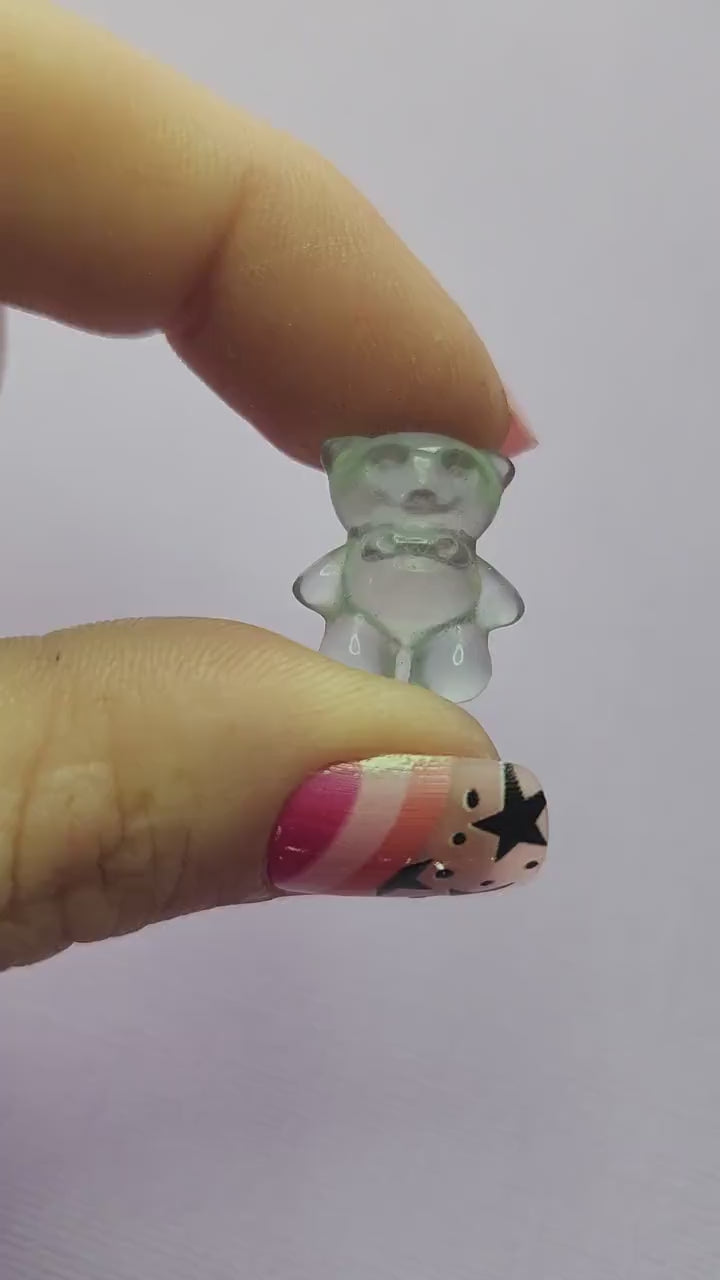 Smooth close-up video of a single fluorite mini bear carving held in hand, showing polished details and natural bands of purple, green and blue fluorite against a lavender backdrop. Ideal for fluorite carvings, mini crystal animals and collectible gemstone bears.