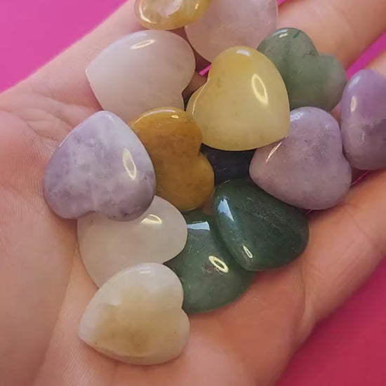 Video showcasing mystery mini crystal heart carvings on a bright pink background. Includes small polished hearts in various crystals such as Amethyst, Rose Quartz, Clear Quartz, Carnelian, Green Aventurine, Rhodonite, and other popular healing stones. Perfect for crystal collectors, crystal healing enthusiasts, gemstone lovers, and spiritual gifts.