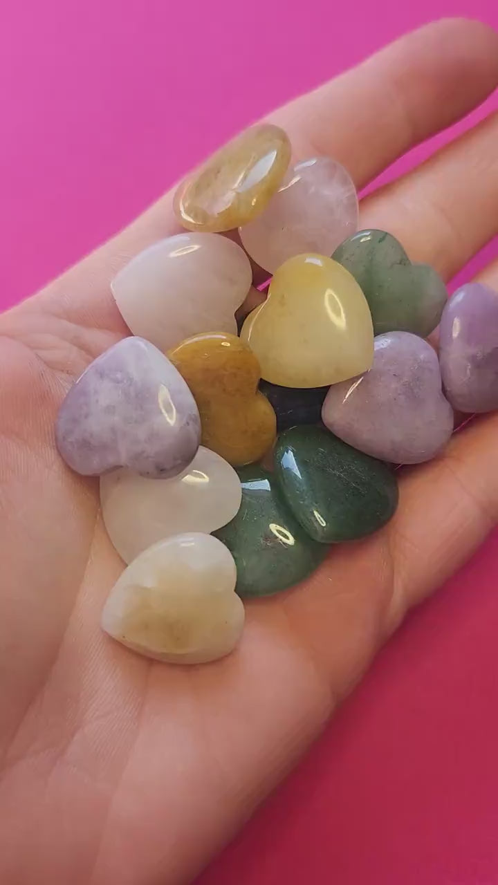 Video showcasing mystery mini crystal heart carvings on a bright pink background. Includes small polished hearts in various crystals such as Amethyst, Rose Quartz, Clear Quartz, Carnelian, Green Aventurine, Rhodonite, and other popular healing stones. Perfect for crystal collectors, crystal healing enthusiasts, gemstone lovers, and spiritual gifts.
