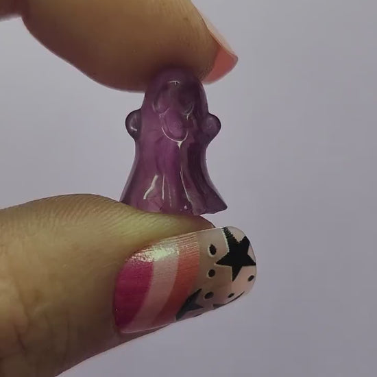 Close-up video of a single fluorite mini ghost carving held in hand, showcasing polished details and natural purple, green and blue fluorite banding against a lavender backdrop. Perfect for fluorite carvings, mini crystal ghosts, and collectible gemstone figures
