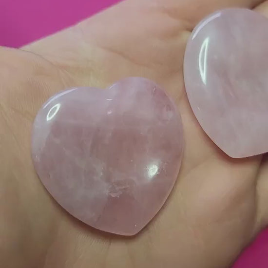 Video of me holding two Rose Quartz heart-shaped worry stones in my hand, showing their soft pink colour and smooth finish against a pink background, calming love crystal for anxiety relief and daily comfort.