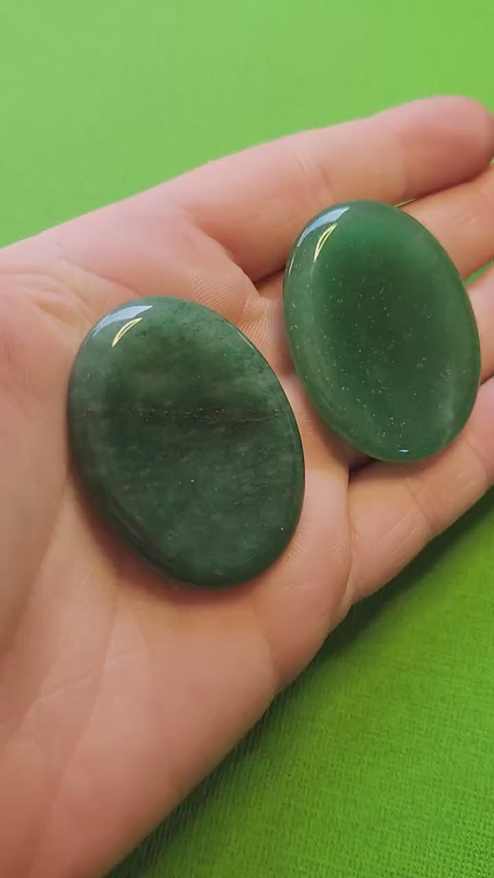 Polished Green Aventurine worry stone held in hand against a green background. Smooth palm-sized crystal for anxiety relief, luck, prosperity, heart chakra healing, meditation, and mindfulness. Perfect for crystal collectors, spiritual practice, or gifting.