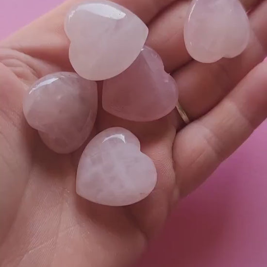 Video of a hand holding and turning a polished rose quartz heart carving against a light pink backdrop, showing its soft pink hue and smooth finish. Gentle lighting highlights the crystal’s natural shine and loving energy. Perfect for crystal healing, self-love rituals, and spiritual decor.