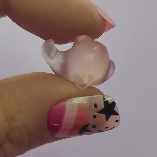 Close-up video of a single fluorite mini whale carving held in hand, showing polished details and natural purple, green and blue fluorite banding as it moves in the light against a lavender backdrop. Ideal for fluorite carvings, mini crystal animals and collectible gemstone whales