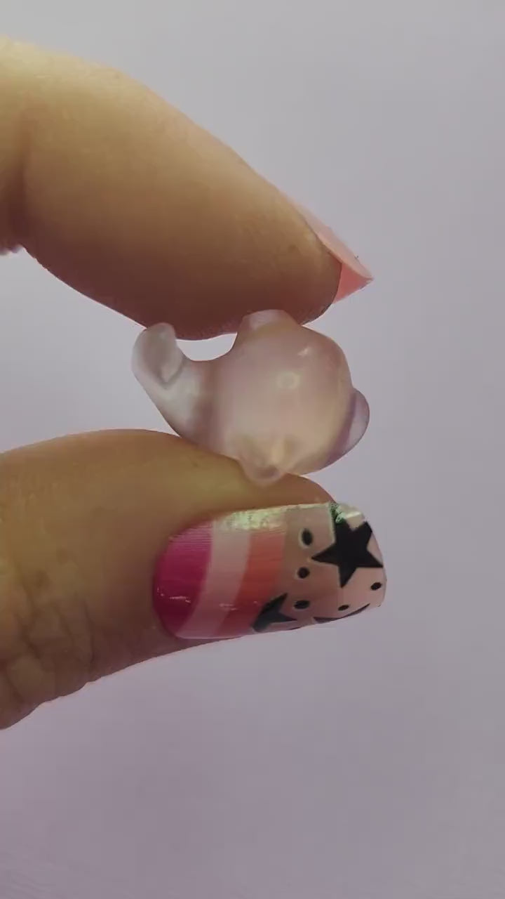 Close-up video of a single fluorite mini whale carving held in hand, showing polished details and natural purple, green and blue fluorite banding as it moves in the light against a lavender backdrop. Ideal for fluorite carvings, mini crystal animals and collectible gemstone whales