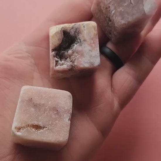 Video of a person showcasing polished Pink Amethyst cubes on a light pink background. Features smooth, square crystal cubes in soft pink hues, perfect for crystal collectors, healing, meditation, and spiritual décor.