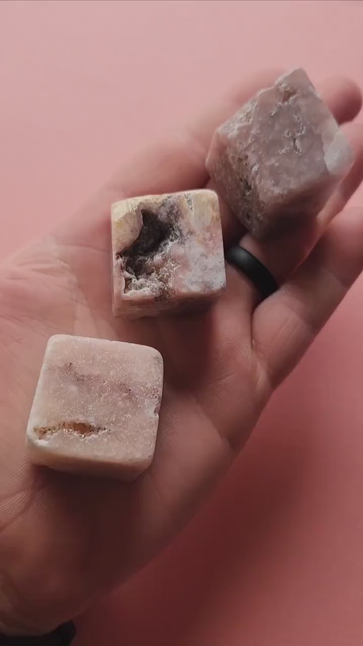 Video of a person showcasing polished Pink Amethyst cubes on a light pink background. Features smooth, square crystal cubes in soft pink hues, perfect for crystal collectors, healing, meditation, and spiritual décor.