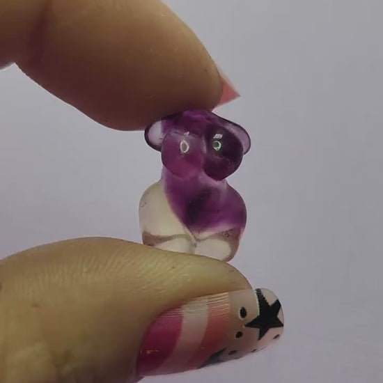 Close-up video of a single fluorite mini goddess body carving held in hand, showing smooth polished details and natural purple, green and blue fluorite banding as it moves in the light against a lavender backdrop. Ideal for fluorite carvings, goddess body crystals and collectible gemstone figures