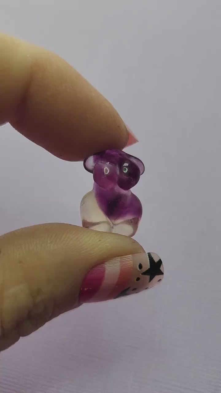 Close-up video of a single fluorite mini goddess body carving held in hand, showing smooth polished details and natural purple, green and blue fluorite banding as it moves in the light against a lavender backdrop. Ideal for fluorite carvings, goddess body crystals and collectible gemstone figures