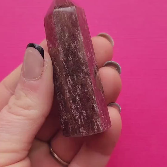 Close-up video of a polished Strawberry Quartz tower held in hand against a pink background, showcasing the pink crystal clarity, sparkly inclusions, and natural gemstone texture; high-vibration healing crystal point for heart chakra work, self-love energy, emotional balance, and spiritual crystal lovers