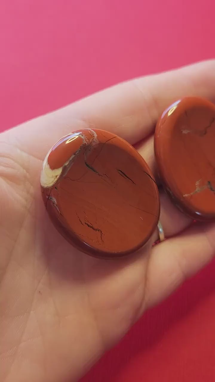 Video of a hand holding several Red Jasper worry stones, showing their deep red color, smooth polished surface, and natural variations. Perfect for grounding, meditation, Reiki, crystal healing, and spiritual energy work. Ideal for crystal collectors and stress relief.