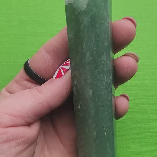 Hand holding a green aventurine crystal tower against a green background showing polished green stone point for luck abundance crystal healing decor and gifting