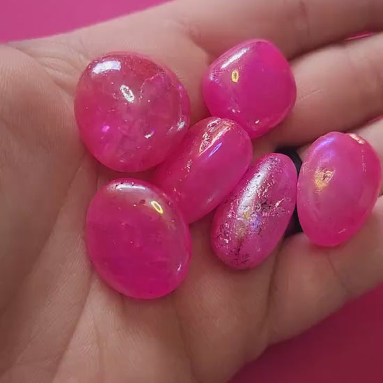 Video of a hand holding shimmering Pink Aura Quartz tumbles that glisten under the light, showing their iridescent pink hues and glossy finish — perfect for crystal collectors, energy healing, and aesthetic crystal displays.