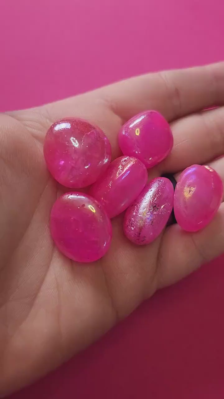 Video of a hand holding shimmering Pink Aura Quartz tumbles that glisten under the light, showing their iridescent pink hues and glossy finish — perfect for crystal collectors, energy healing, and aesthetic crystal displays.