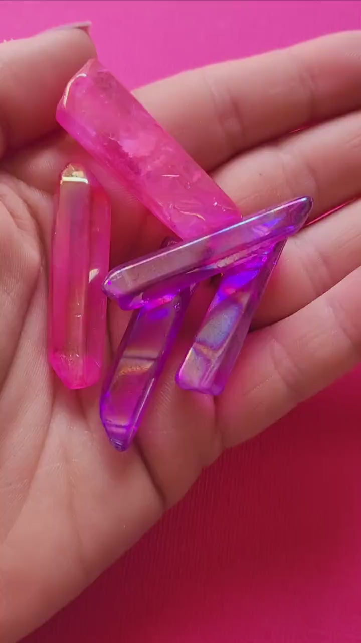Video showcasing Aura Quartz rough points in pink and purple on a pink background. Features natural crystal points with vibrant iridescent hues, perfect for crystal collectors, healing, meditation, and spiritual décor