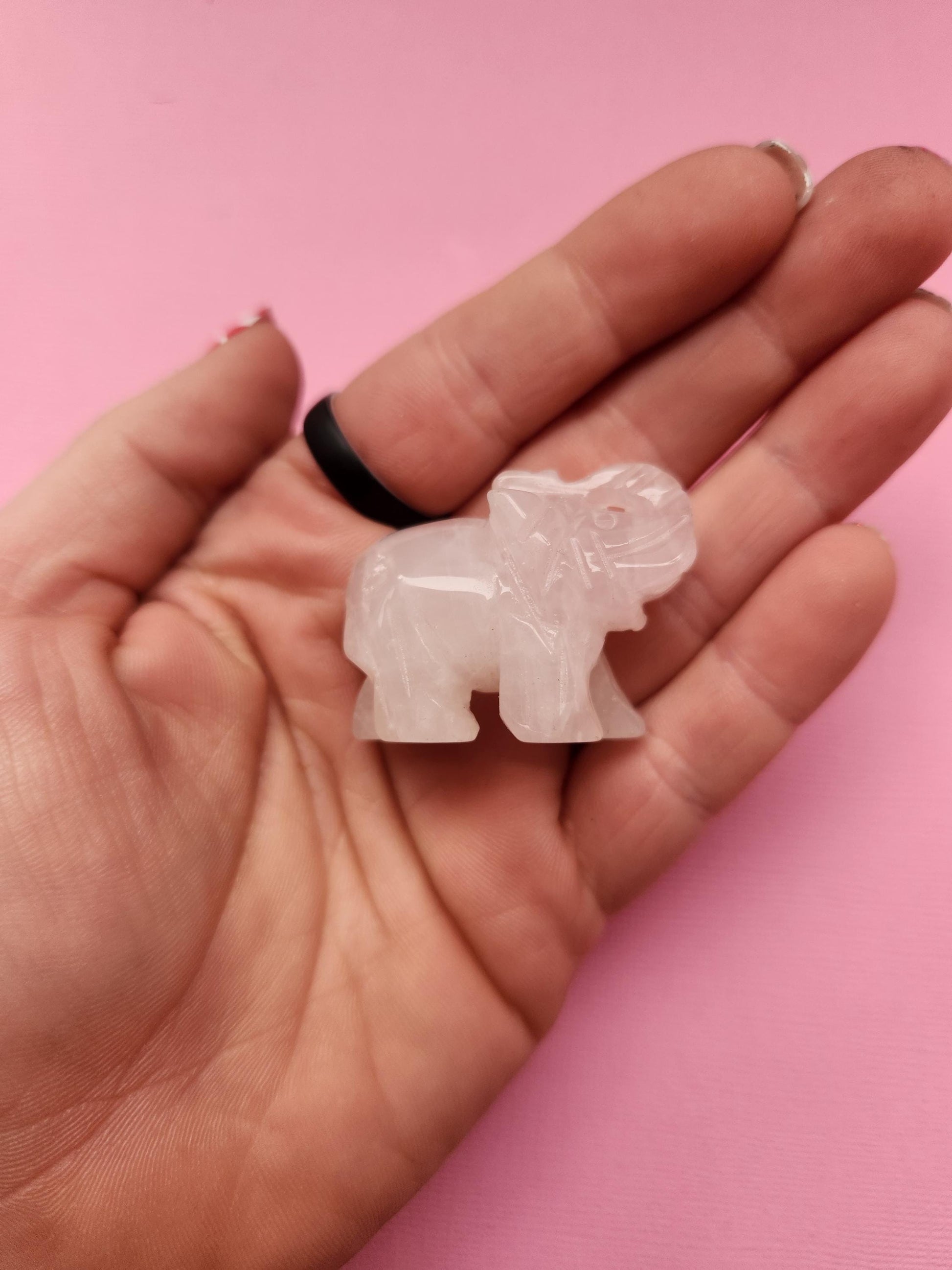 Rose quartz elephant crystal carving held in hand against a pink background, polished gemstone animal figurine showcasing size and detail for crystal collectors and gifts