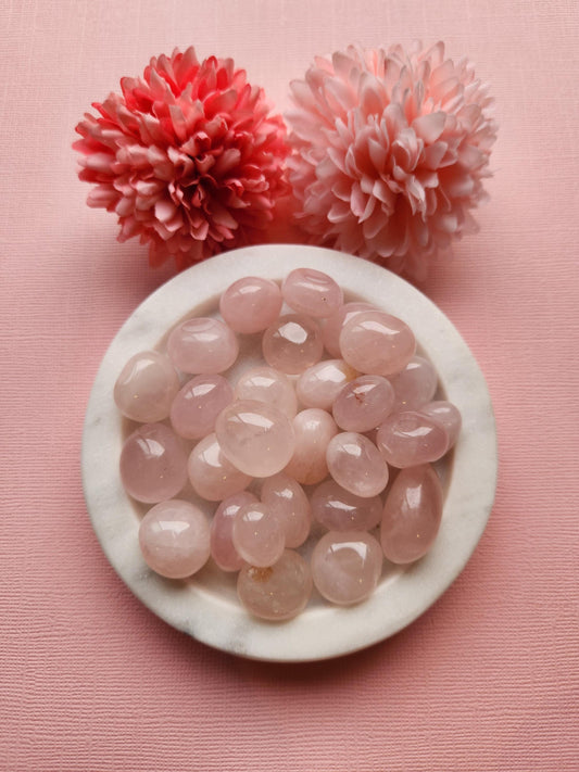 Rose Quartz tumbles displayed on a soft pastel pink background, highlighting their gentle pink hue and smooth, polished finish. These self-love crystals are known for promoting emotional healing, compassion, and heart chakra balance. The pastel backdrop enhances the calming and nurturing energy of the stones, making them ideal for meditation, gifting, or crystal healing collections.