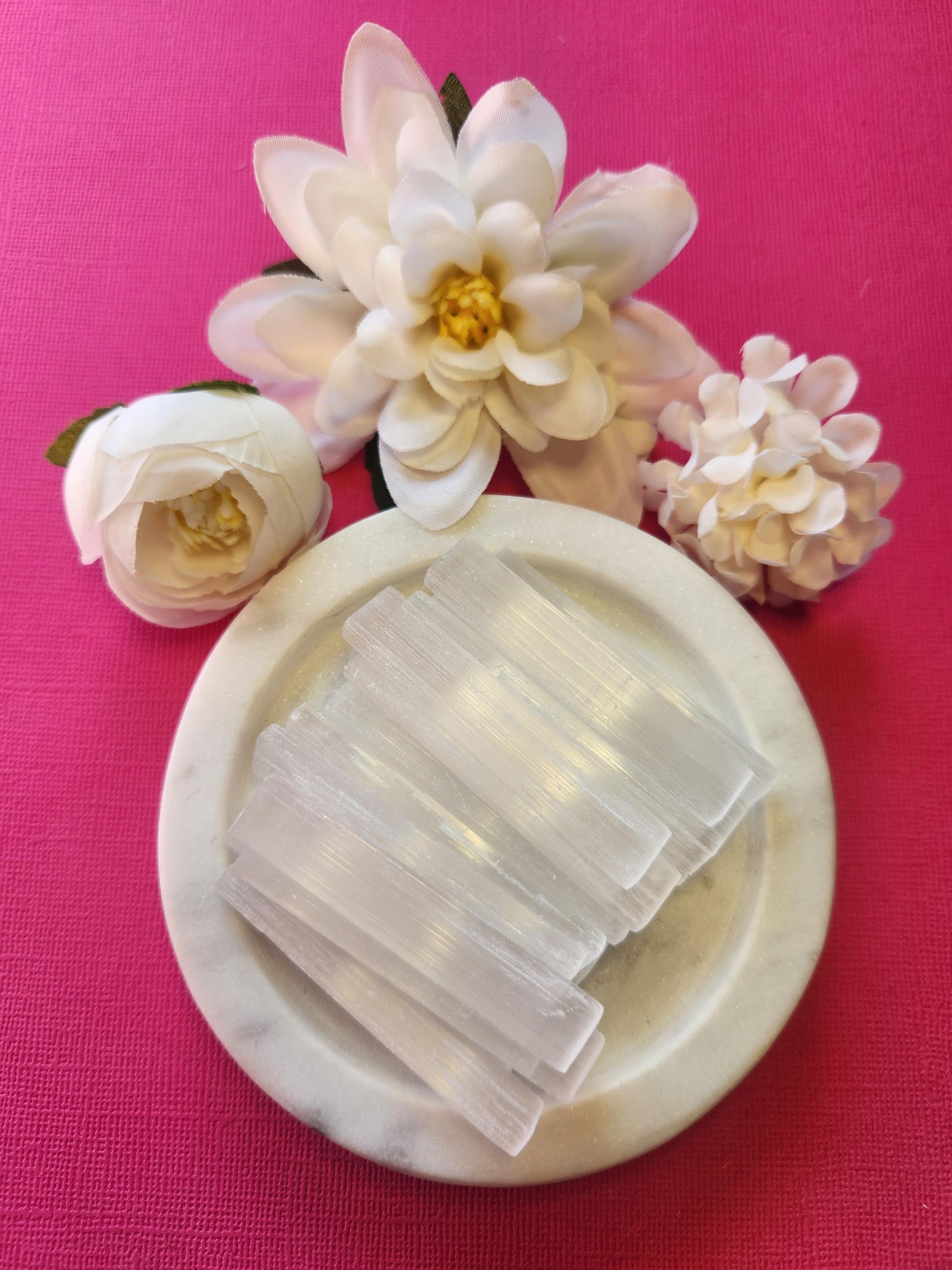 Selenite sticks displayed on a bright pink background, highlighting their smooth, white, translucent appearance. These natural crystal wands are commonly used for energy cleansing, aura clearing, and spiritual protection. Ideal for Reiki, meditation, and charging other crystals. The vibrant pink backdrop contrasts beautifully with the calming, high-vibration energy of the selenite, making it perfect for healers and crystal collectors.
