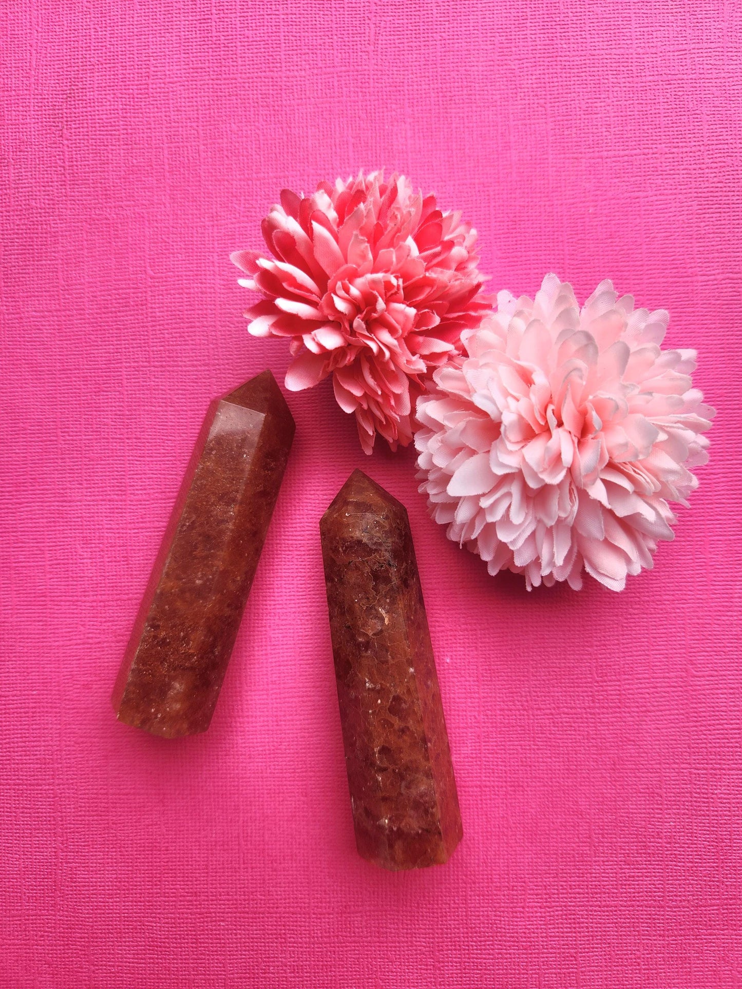 High-quality Strawberry Quartz crystal towers side by side on a pink background with soft flower props, polished pink healing crystal points for grounding energy, self-love, emotional balance, and manifesting positivity, aesthetic gemstone display for crystal collectors and spiritual shops
