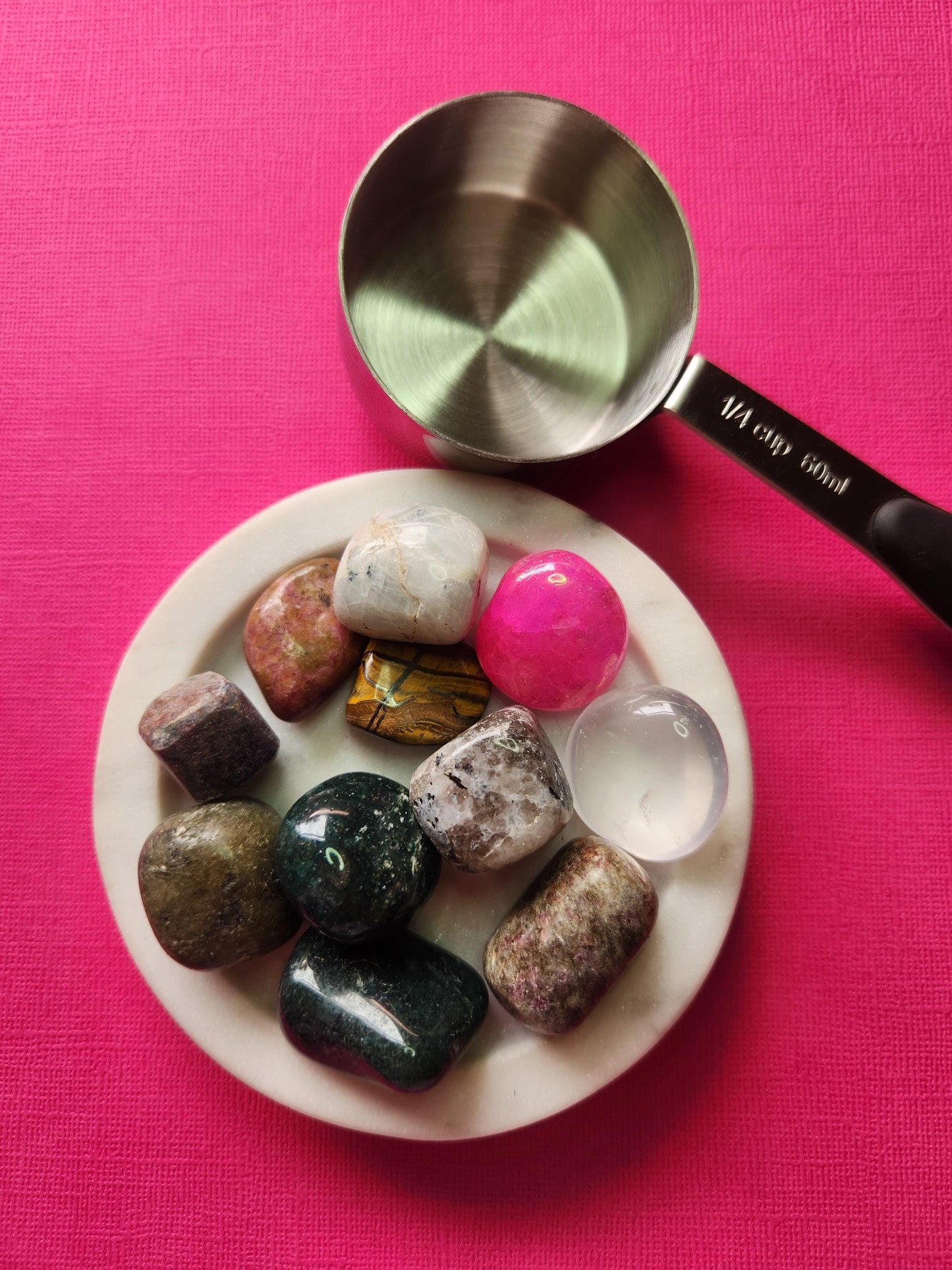 Crystal confetti sample scoop displayed in a white dish against a pink backdrop, showing a 1/4 cup mix with a guaranteed minimum of 10 polished gemstone tumbles. High-detail photo featuring assorted crystals for intention setting, crafting, spellwork, crystal collectors, and metaphysical Etsy listings with strong SEO keywords